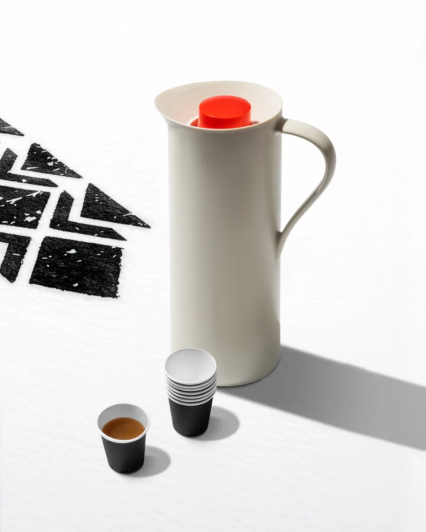 A coffee flask with paper cups, shot on white with the pattern shadow.