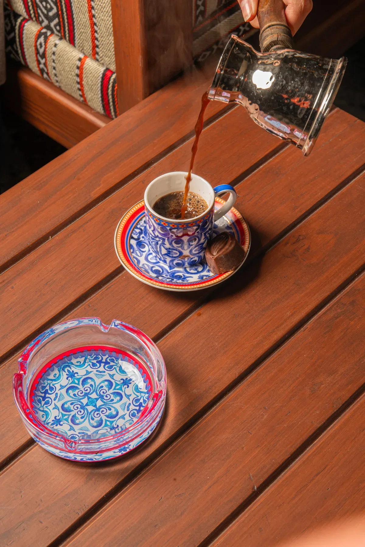 Coffee poured into a patterned cup on a wooden table.