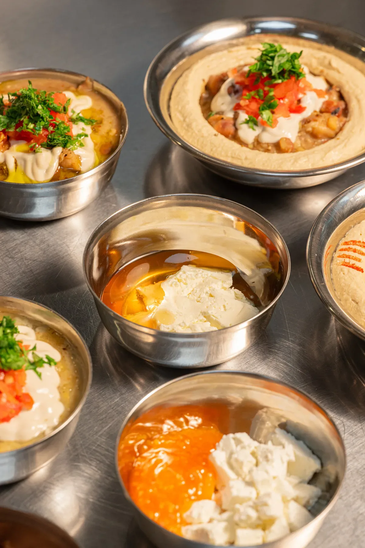 Bowls of mezze lined up on the steel pass.