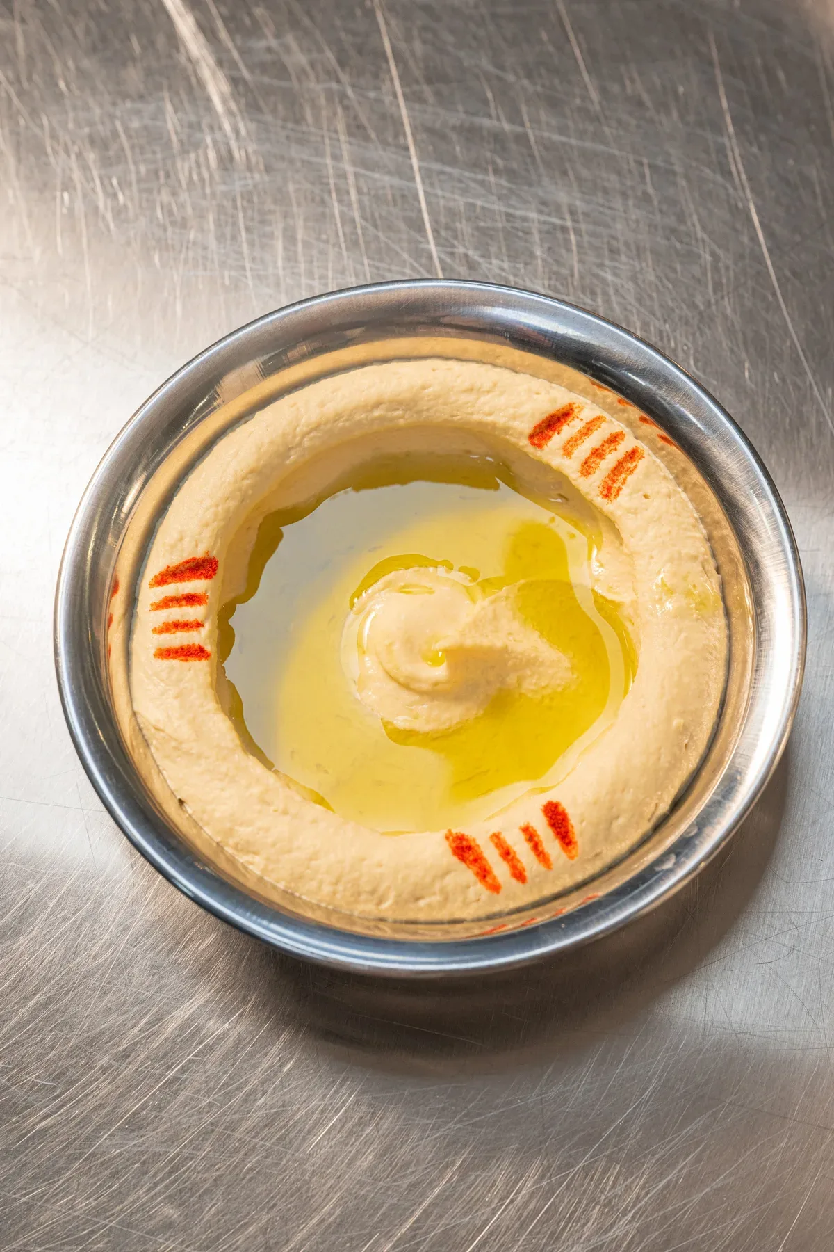 A bowl of hummus with olive oil, overhead.