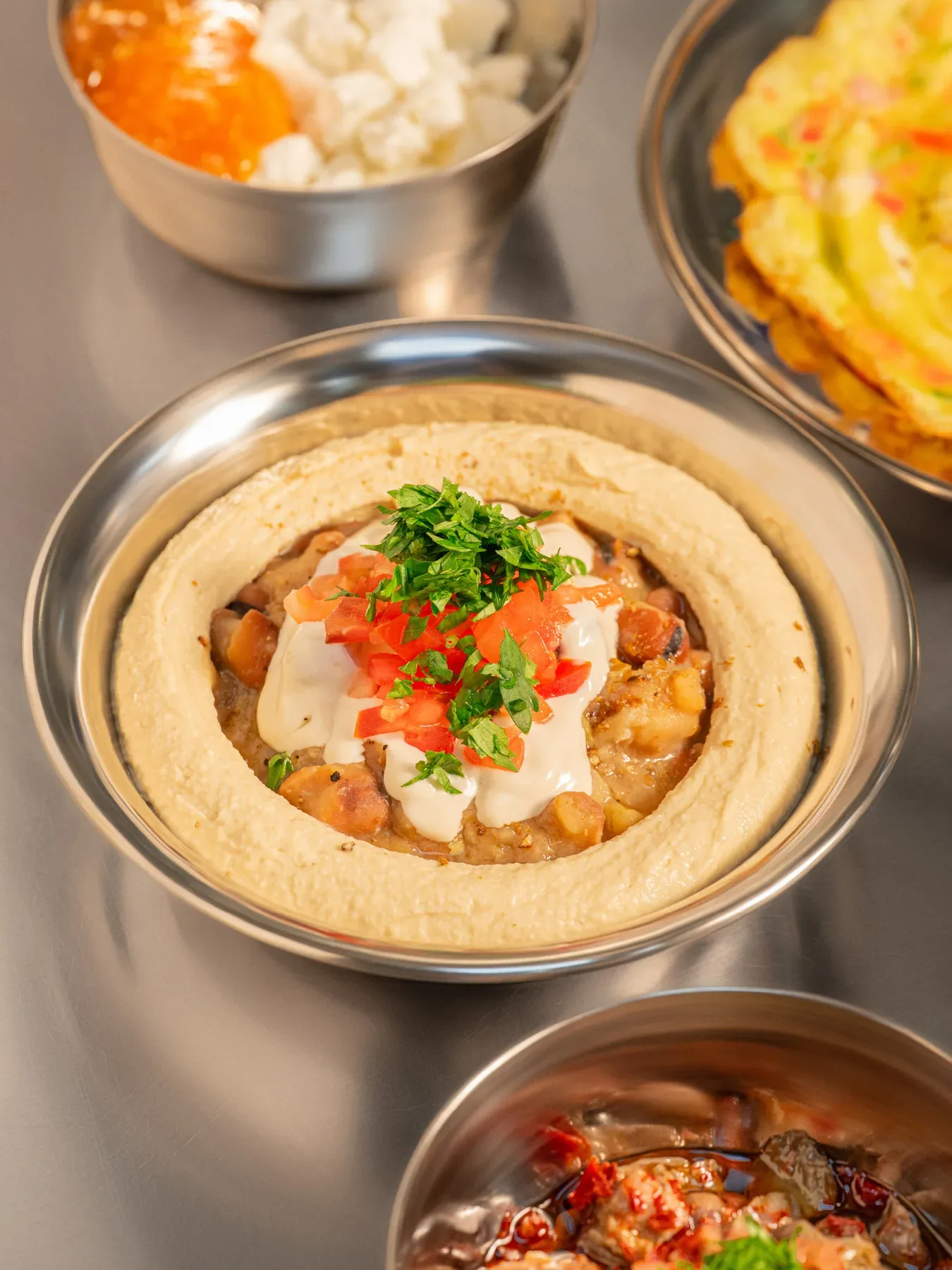 A breakfast mezze flat lay with hummus at the centre.