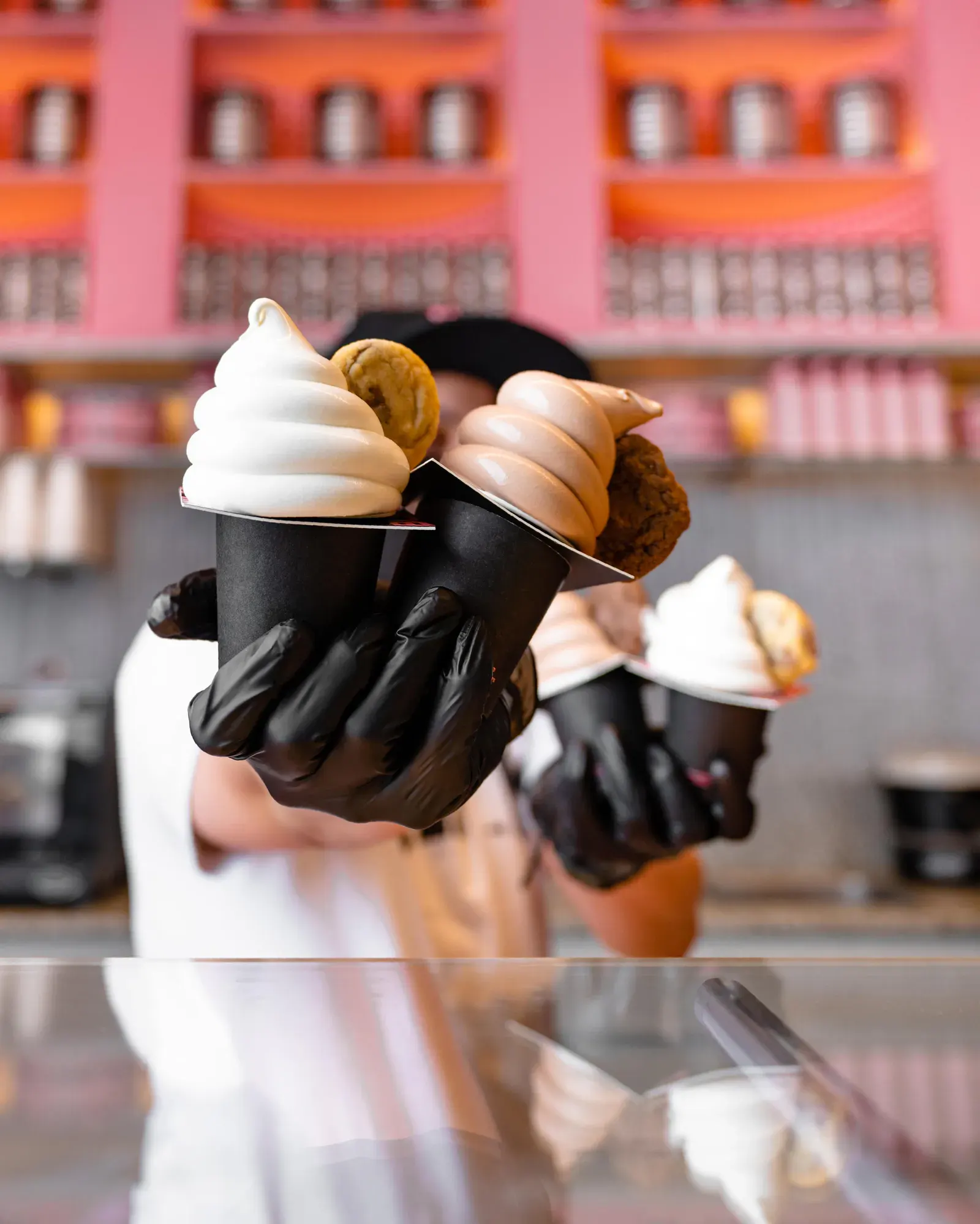 Cones and cookies held in gloves, in front of the counter.