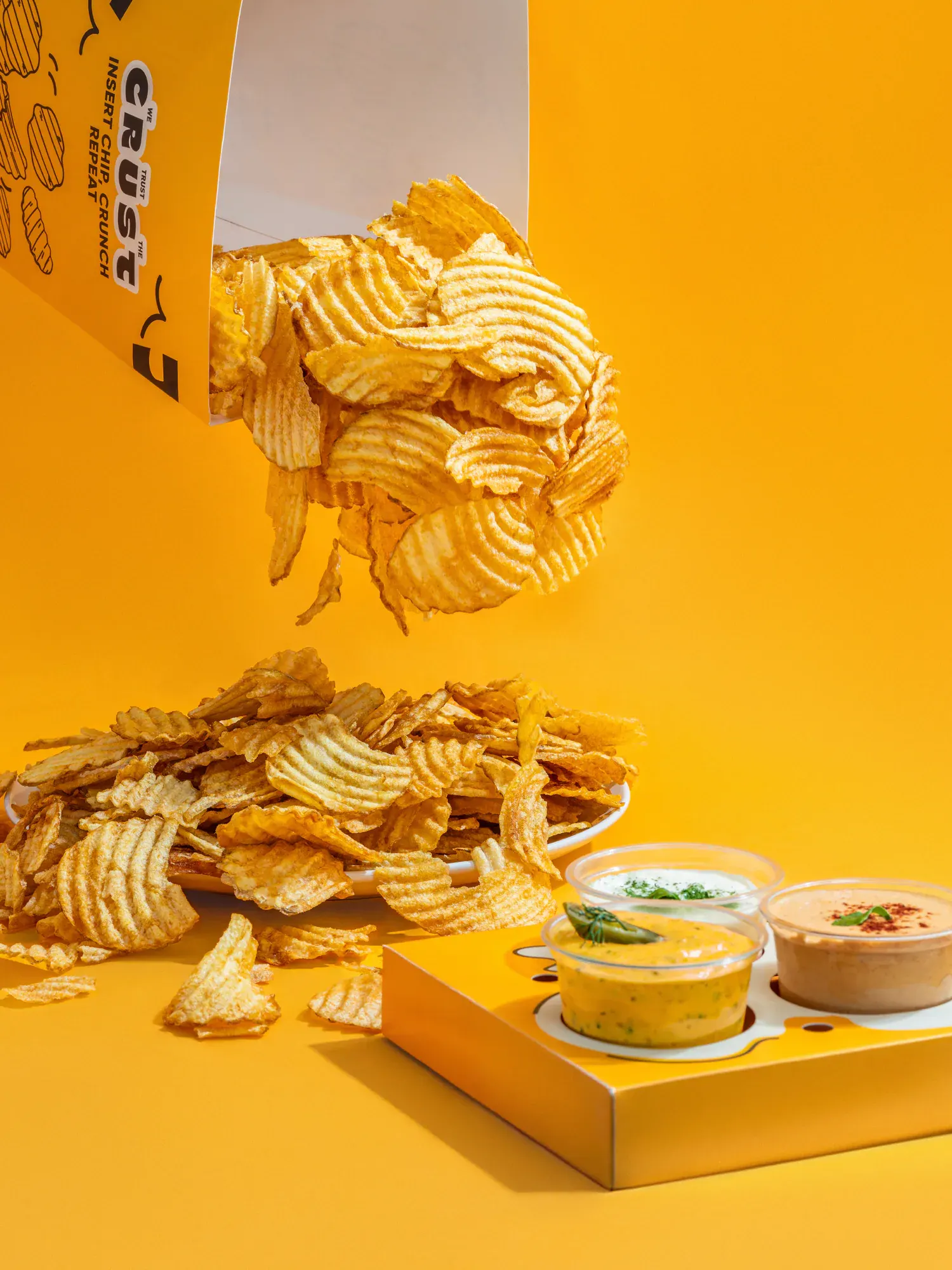 The chips shot falling, on a plinth built in the same yellow as the box.