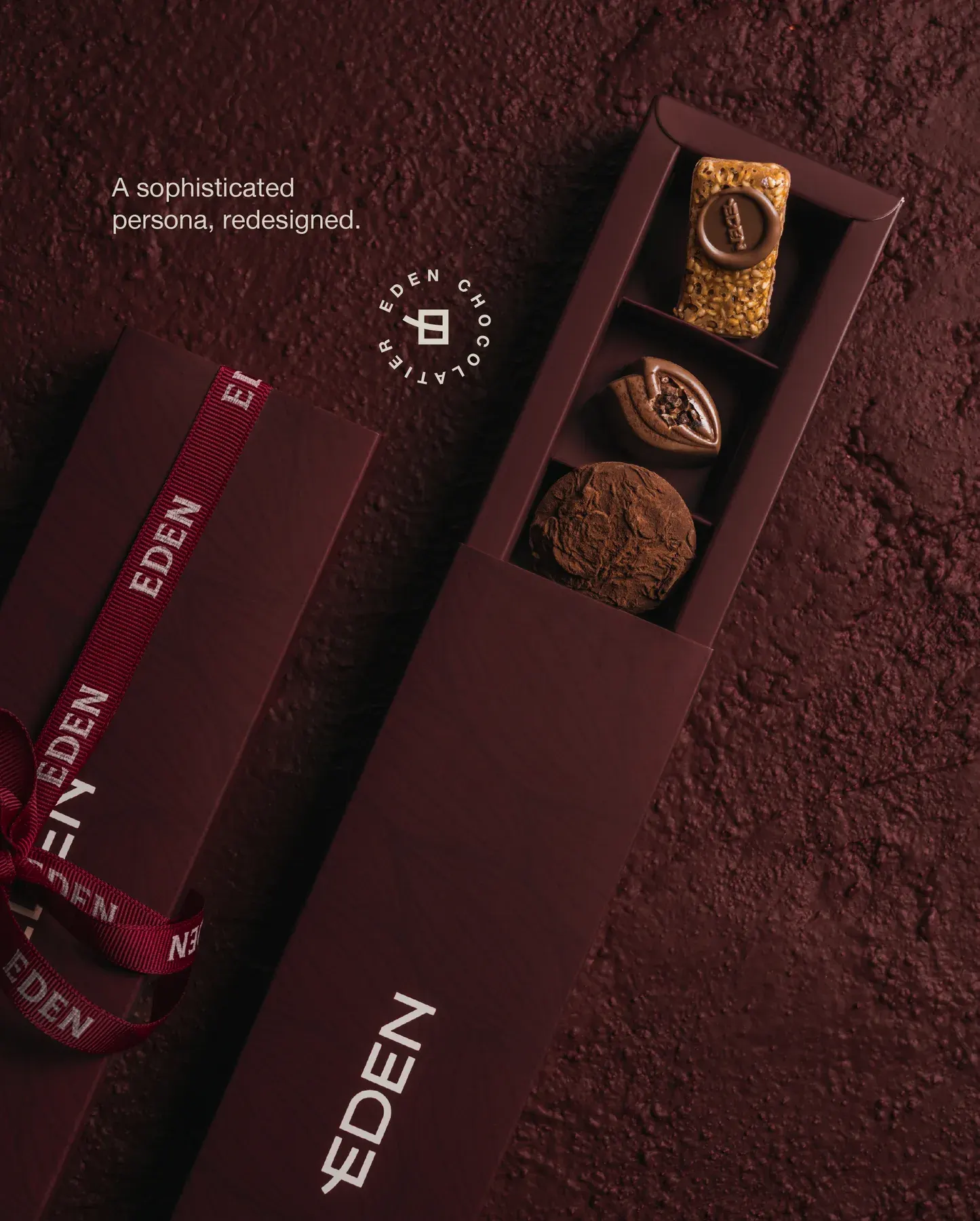 A slim Eden box open on a bed of cocoa with the round brand stamp.