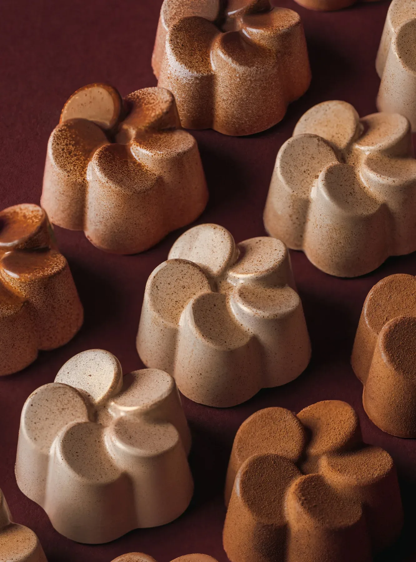 Two tone flower shaped bonbons scattered across burgundy.