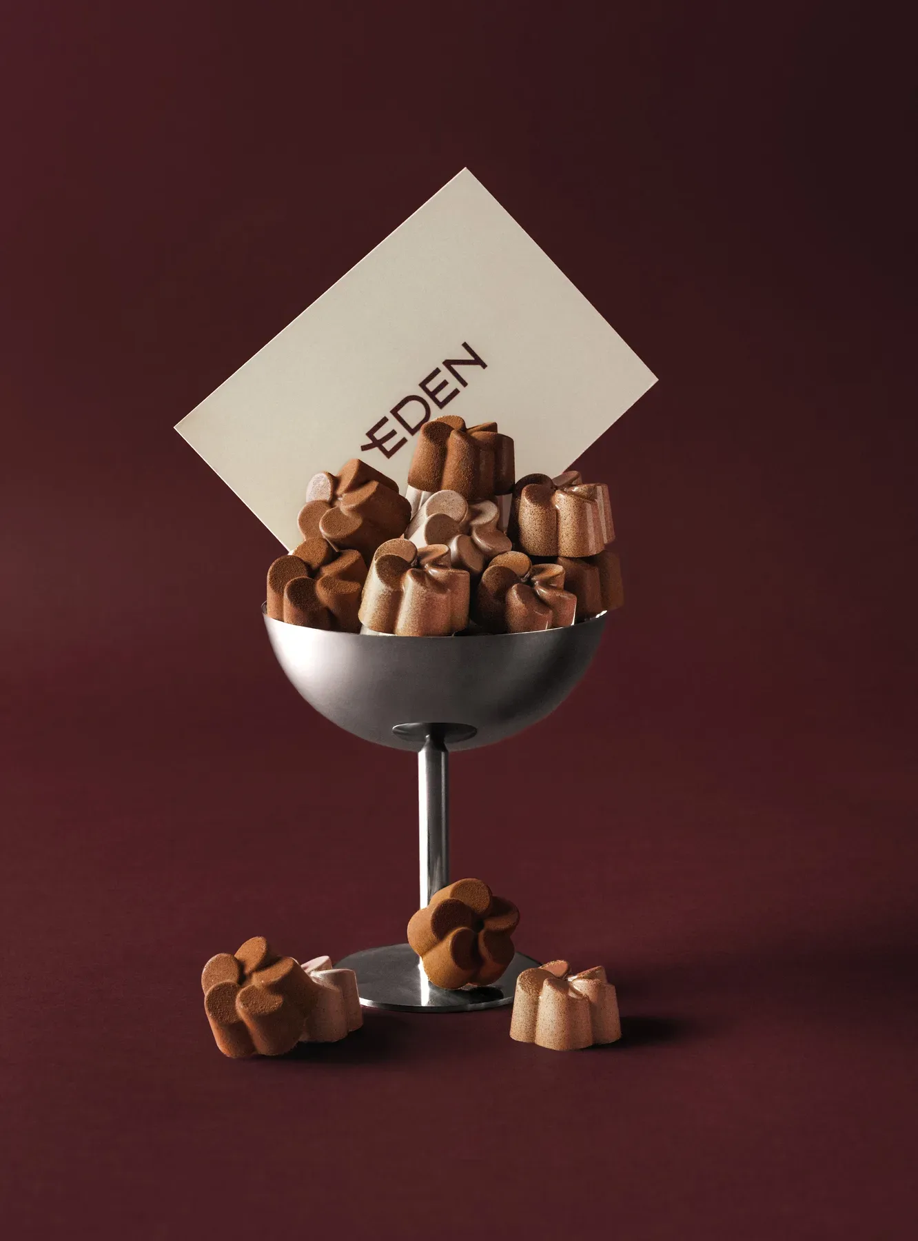 A silver coupe filled with chocolates under an Eden card.
