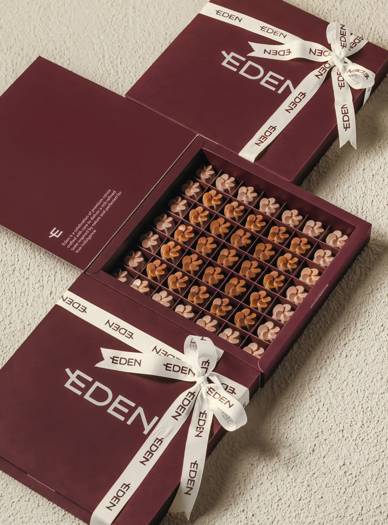 Ribboned Eden boxes beside an open tray of chocolates.