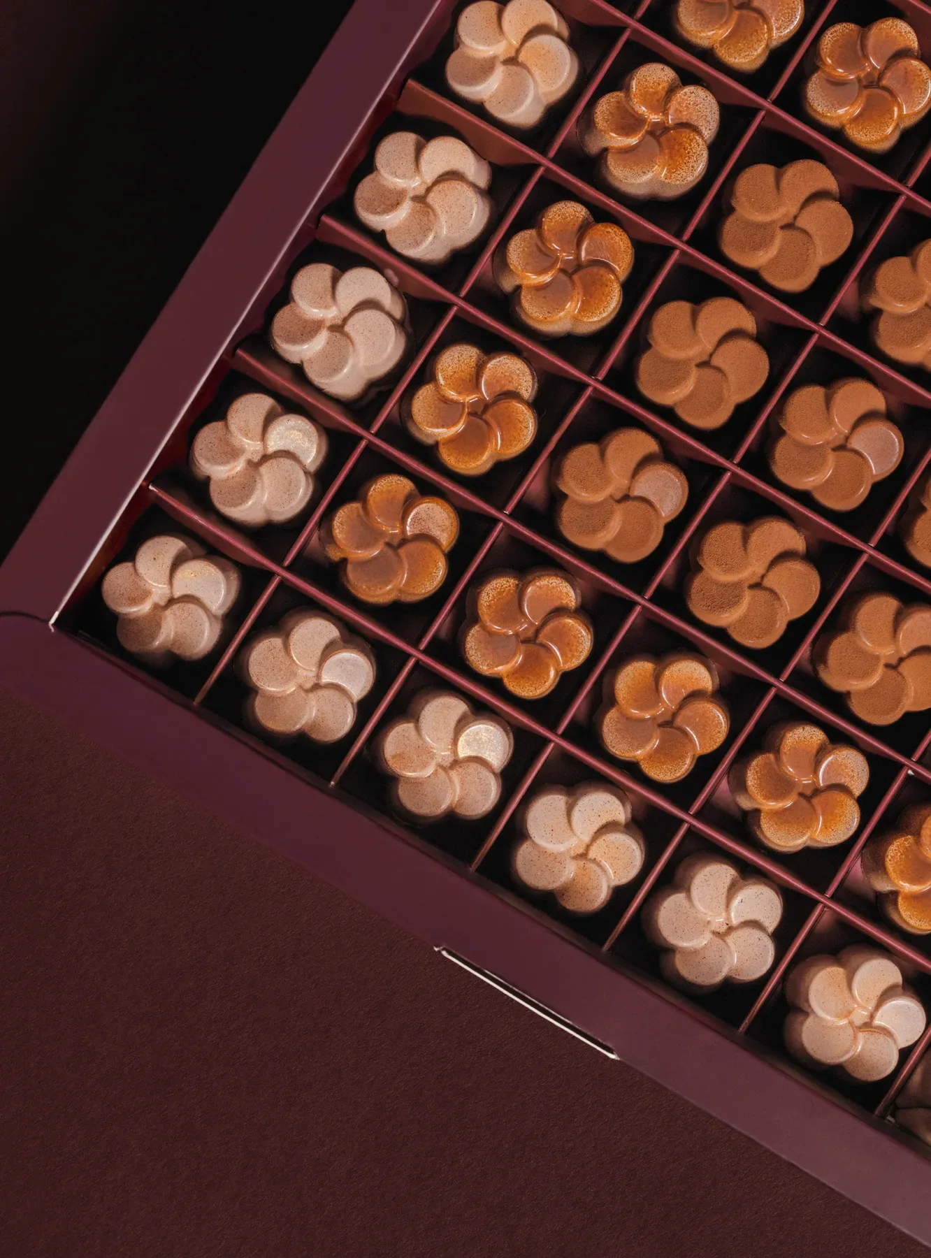 An open Eden box of flower shaped pralines, shot on an angle.