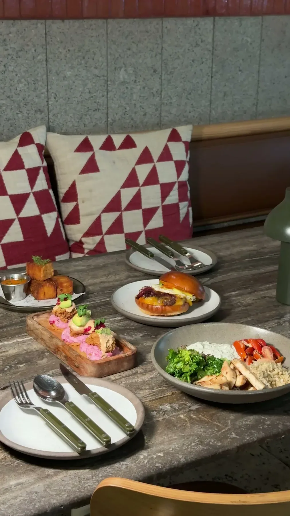 A lunch table at Folio with a burger, a bowl and small plates.