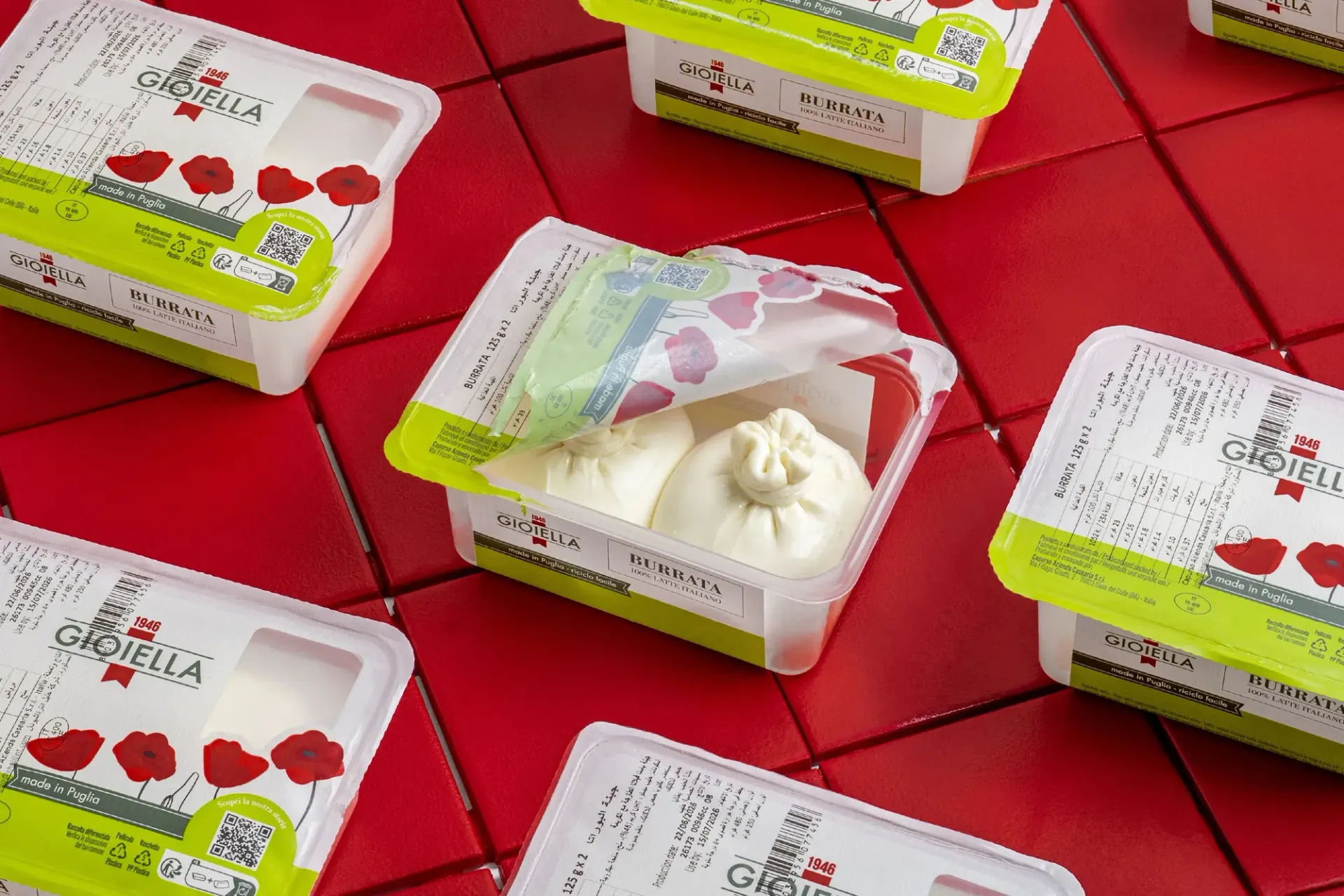 Tubs of burrata laid out on red tiles, one opened.