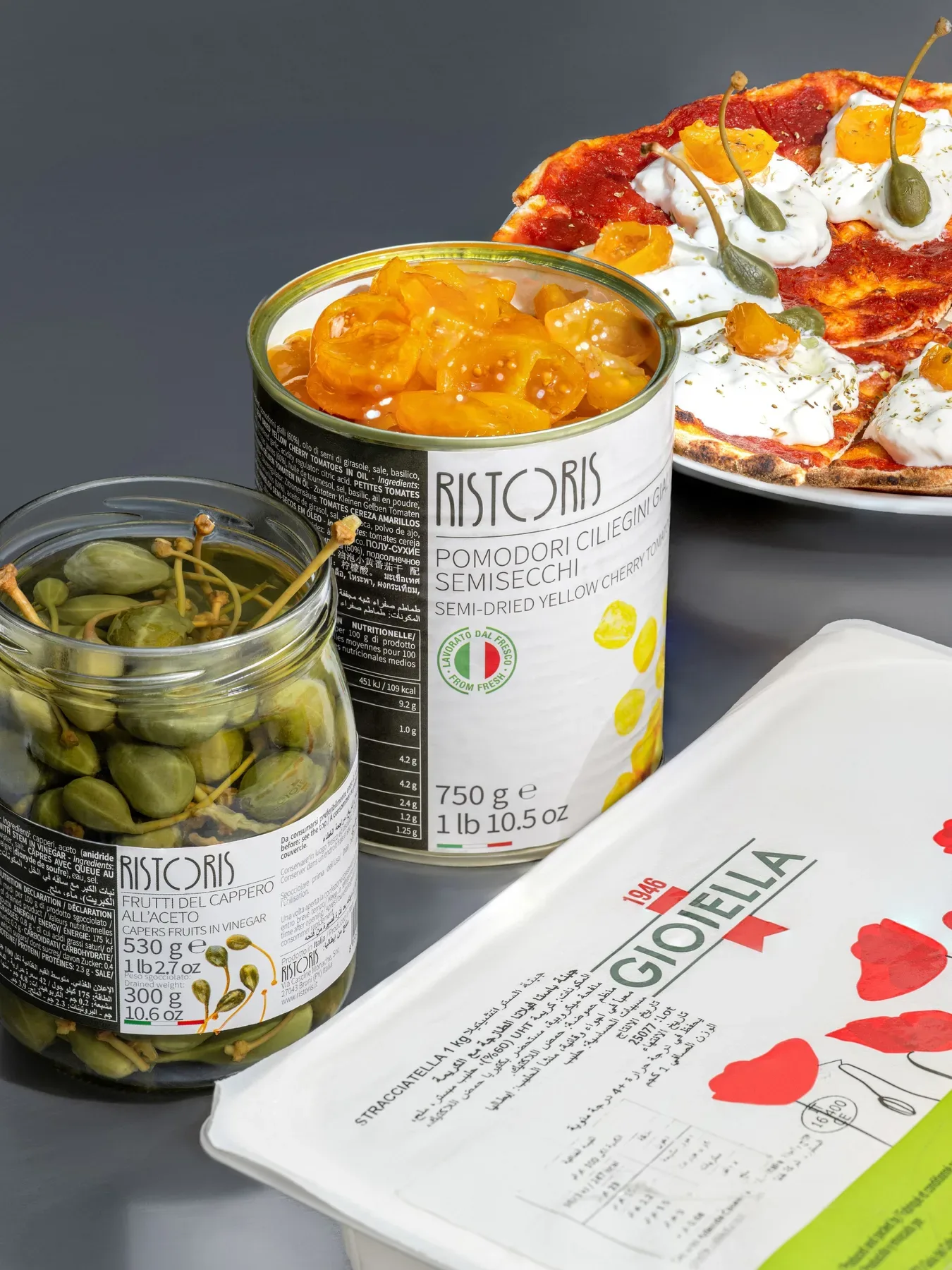 Tomatoes, capers and burrata in their packs, with the pizza they make above.