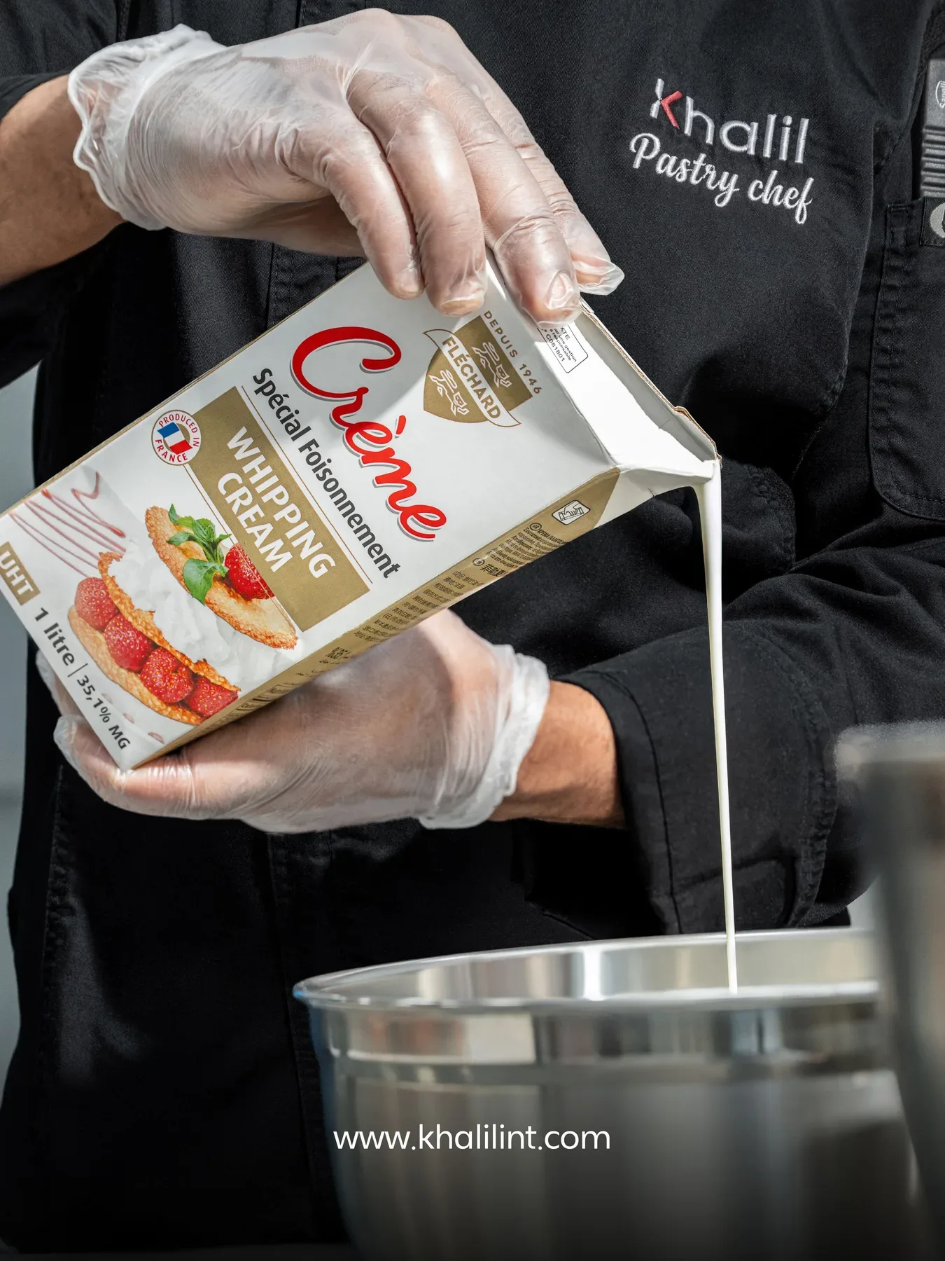 A pastry chef pouring cooking cream into a steel bowl.