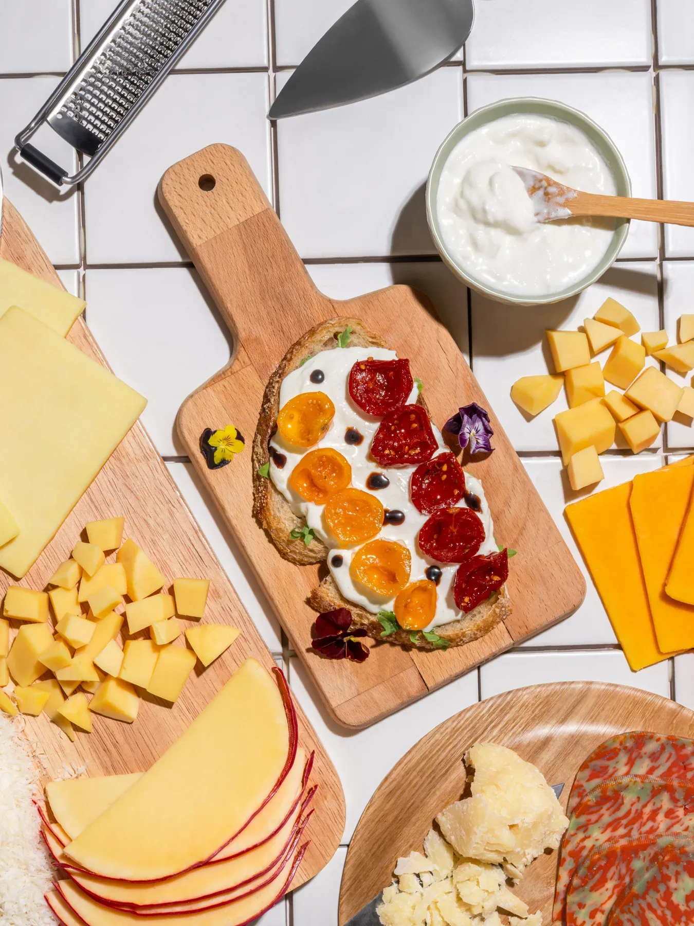 A cheese board flat lay with burrata toast, cubes and slices.