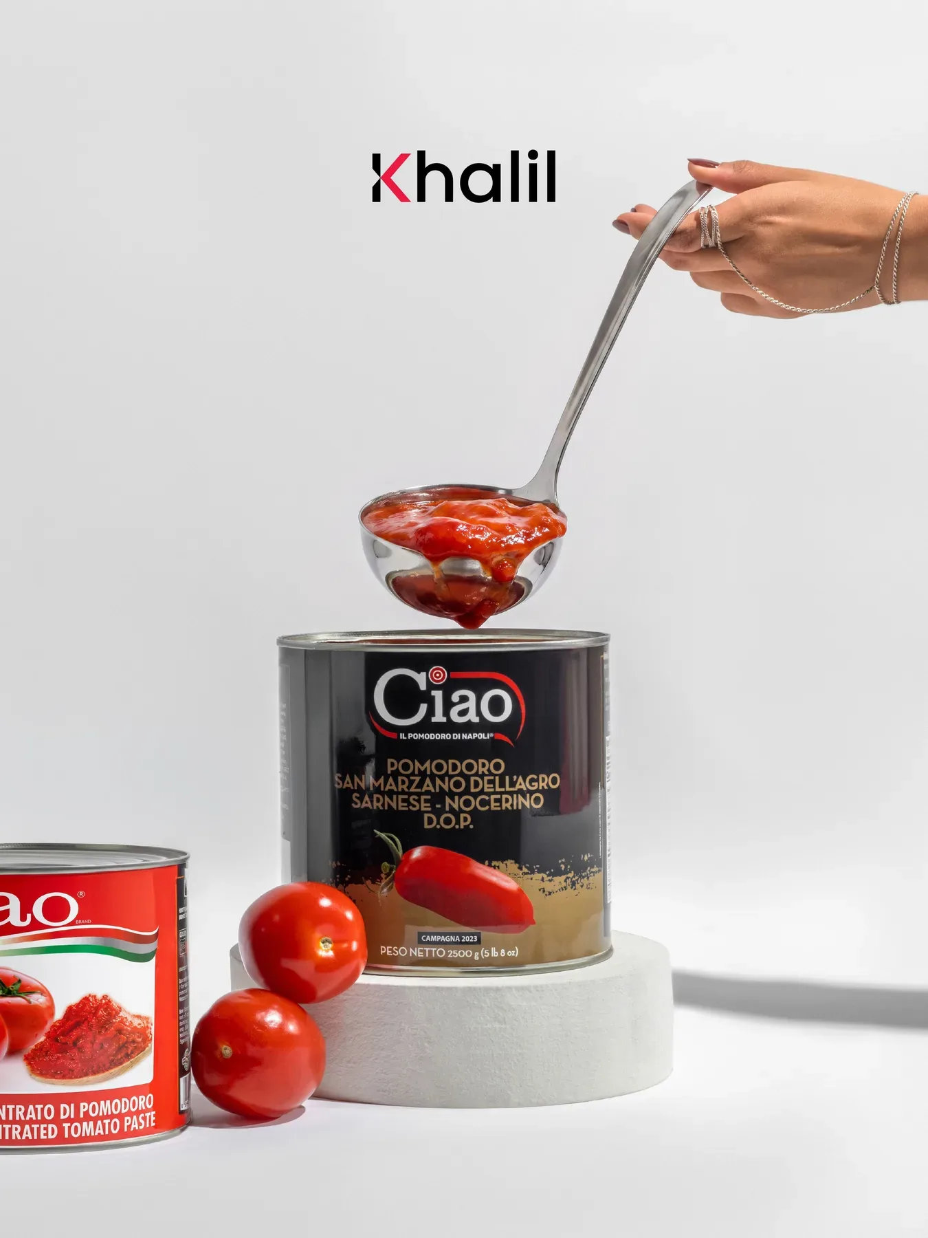 Peeled tomatoes lifted from the can with a ladle on a white set.