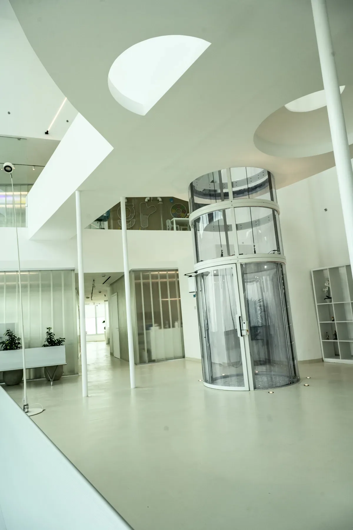 A white lobby with a cylindrical glass door.