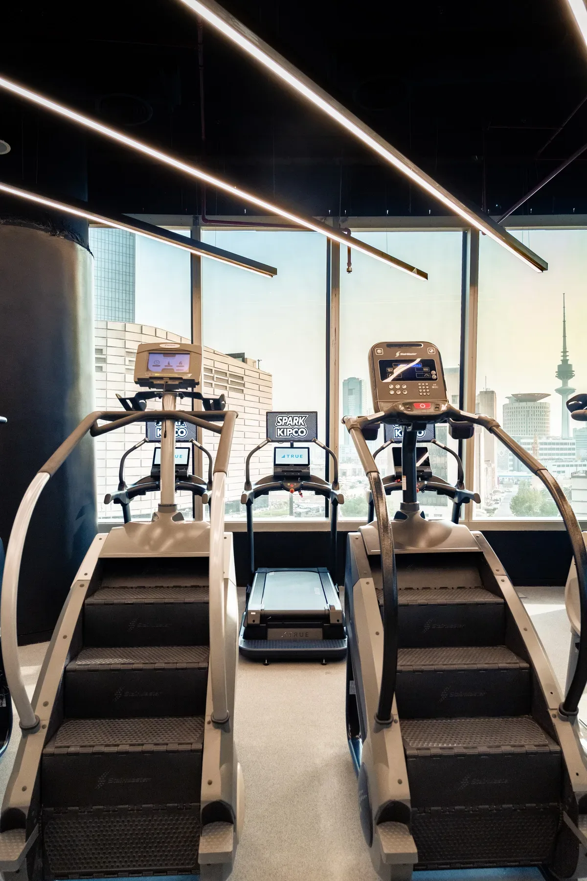 Cardio machines facing the city through full height glass.