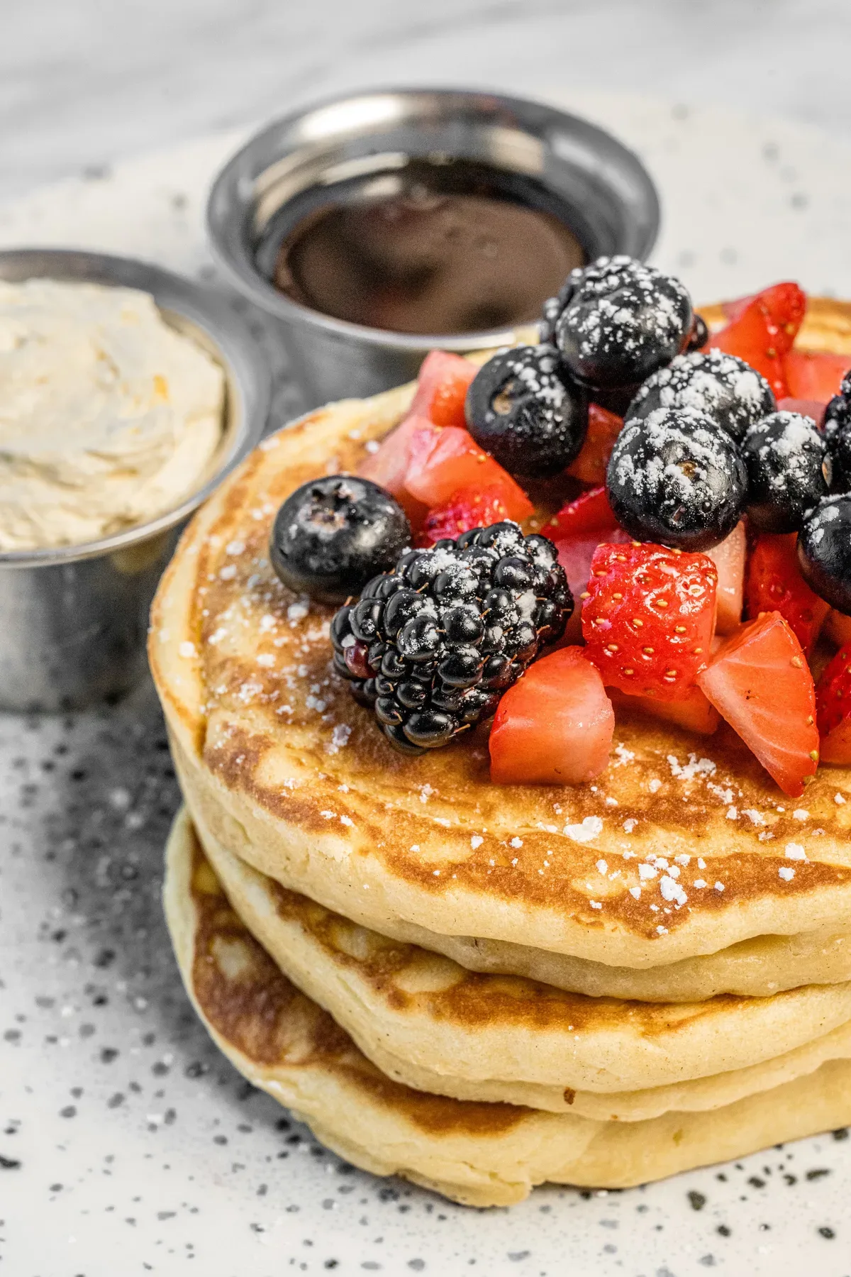 A pancake stack with berries, cream and chocolate sauce.