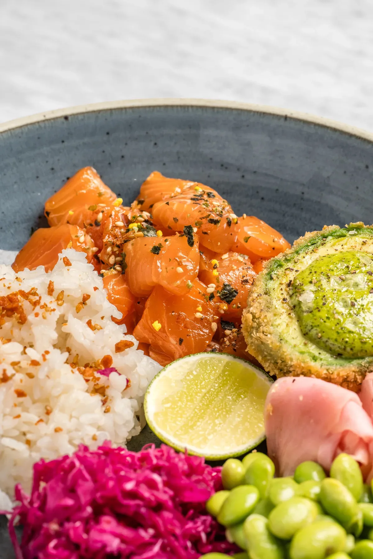 A salmon poke bowl shot overhead on marble.