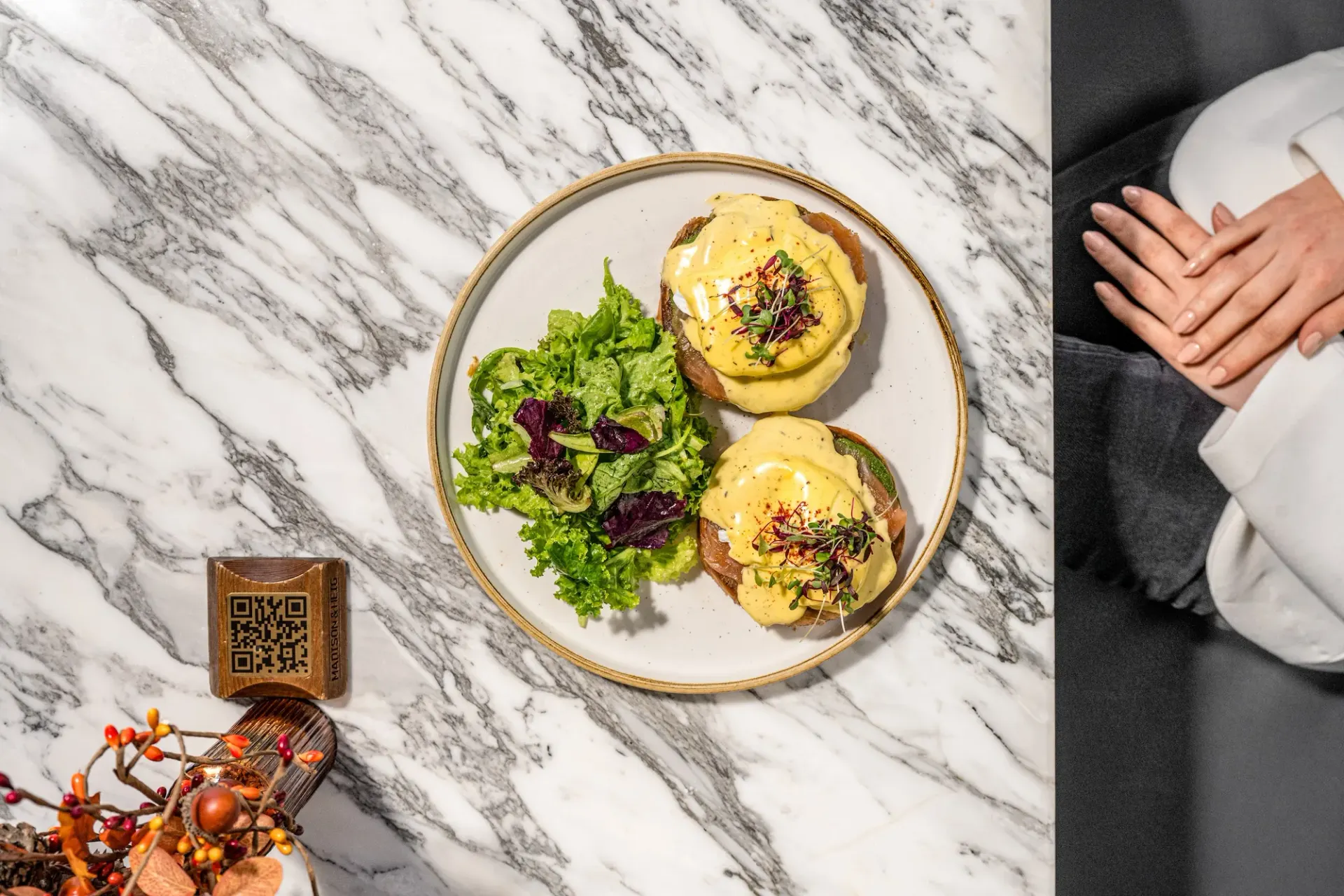 Eggs benedict with a side salad on marble.