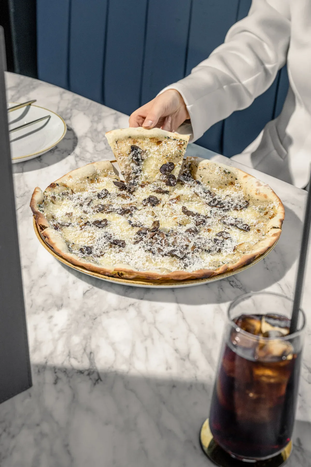 A truffle flatbread being set down on a marble table.