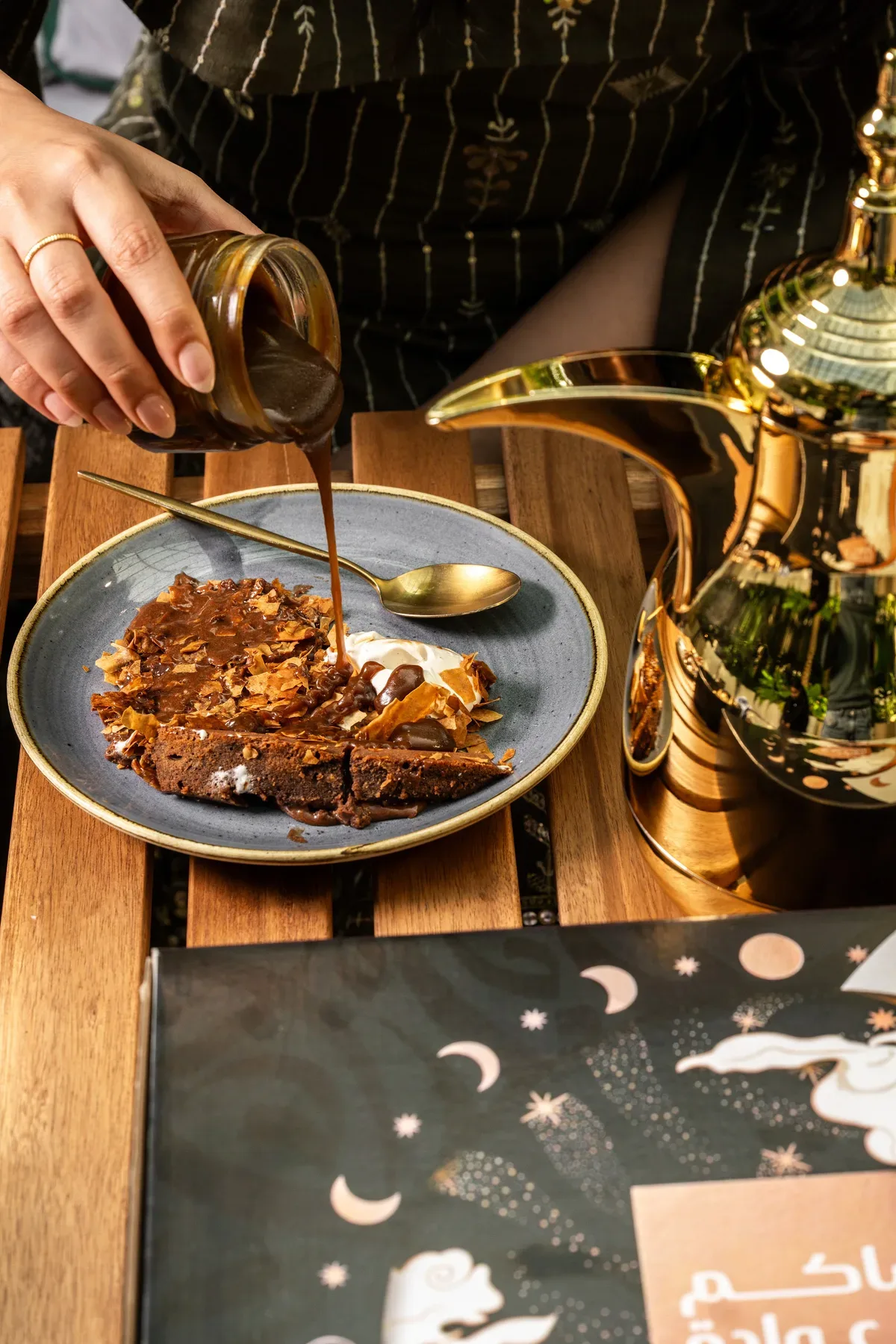 Arabic coffee poured beside a dessert plate, with a brass dallah.