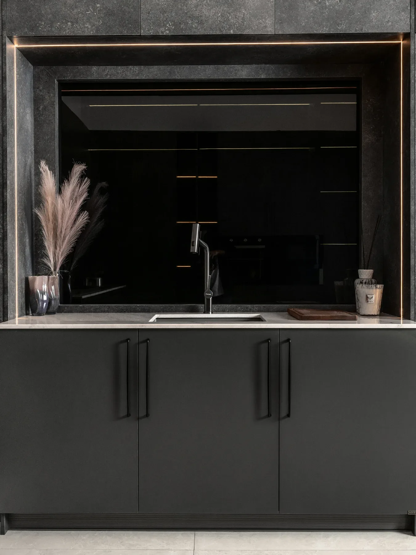 A compact kitchen in dark grey with a black sink niche.