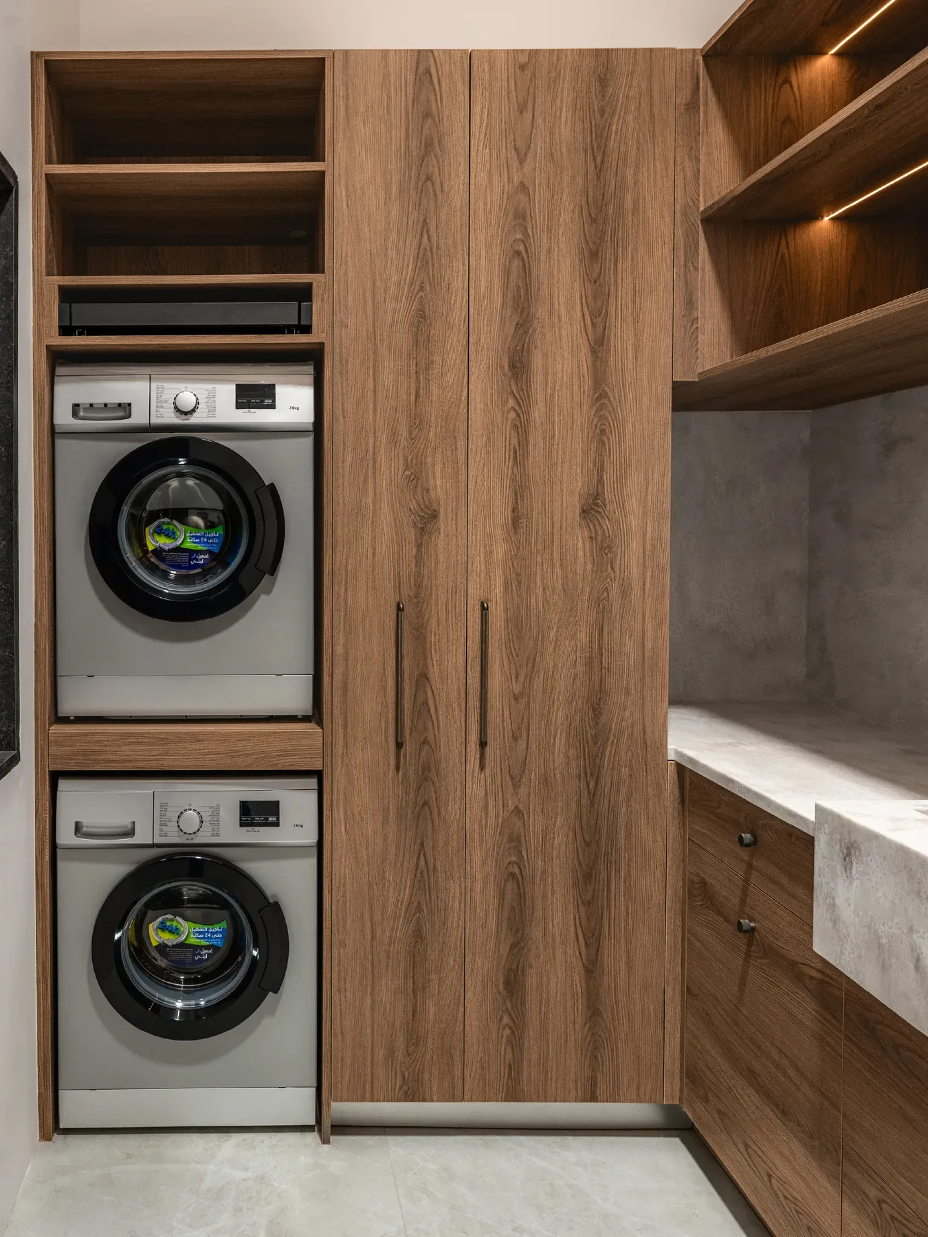 A laundry unit with a stacked washer and dryer inside walnut joinery.
