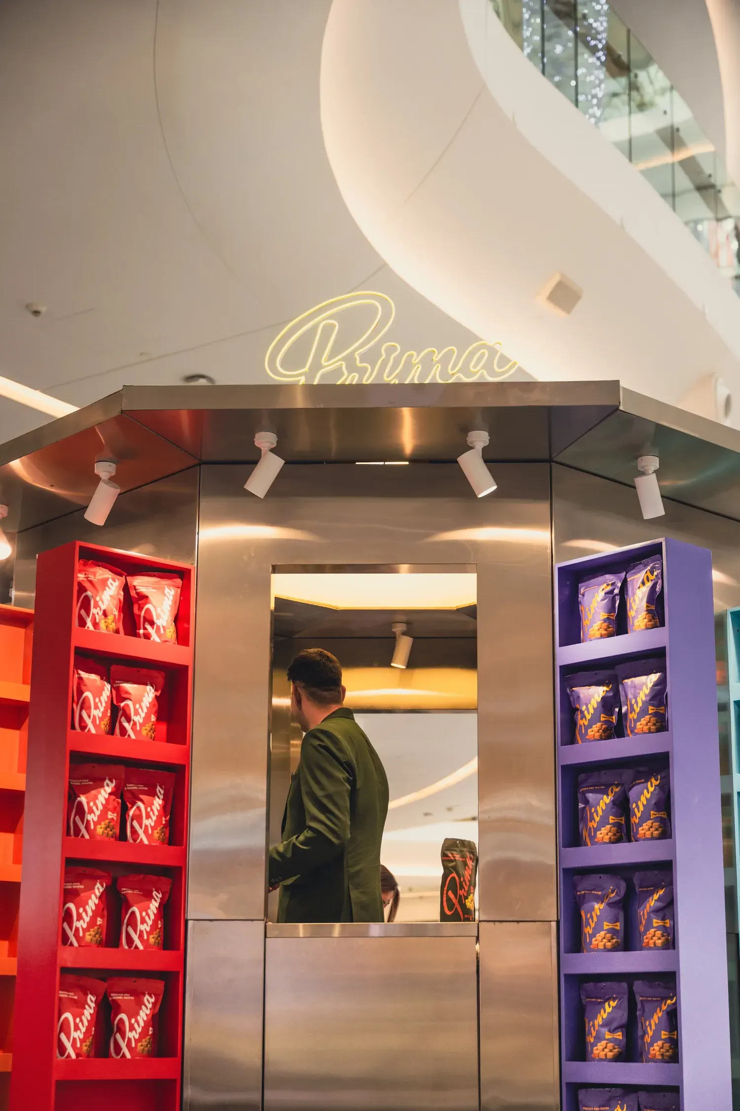 The serving window of the Prima pop-up between the red and purple flavour shelves.