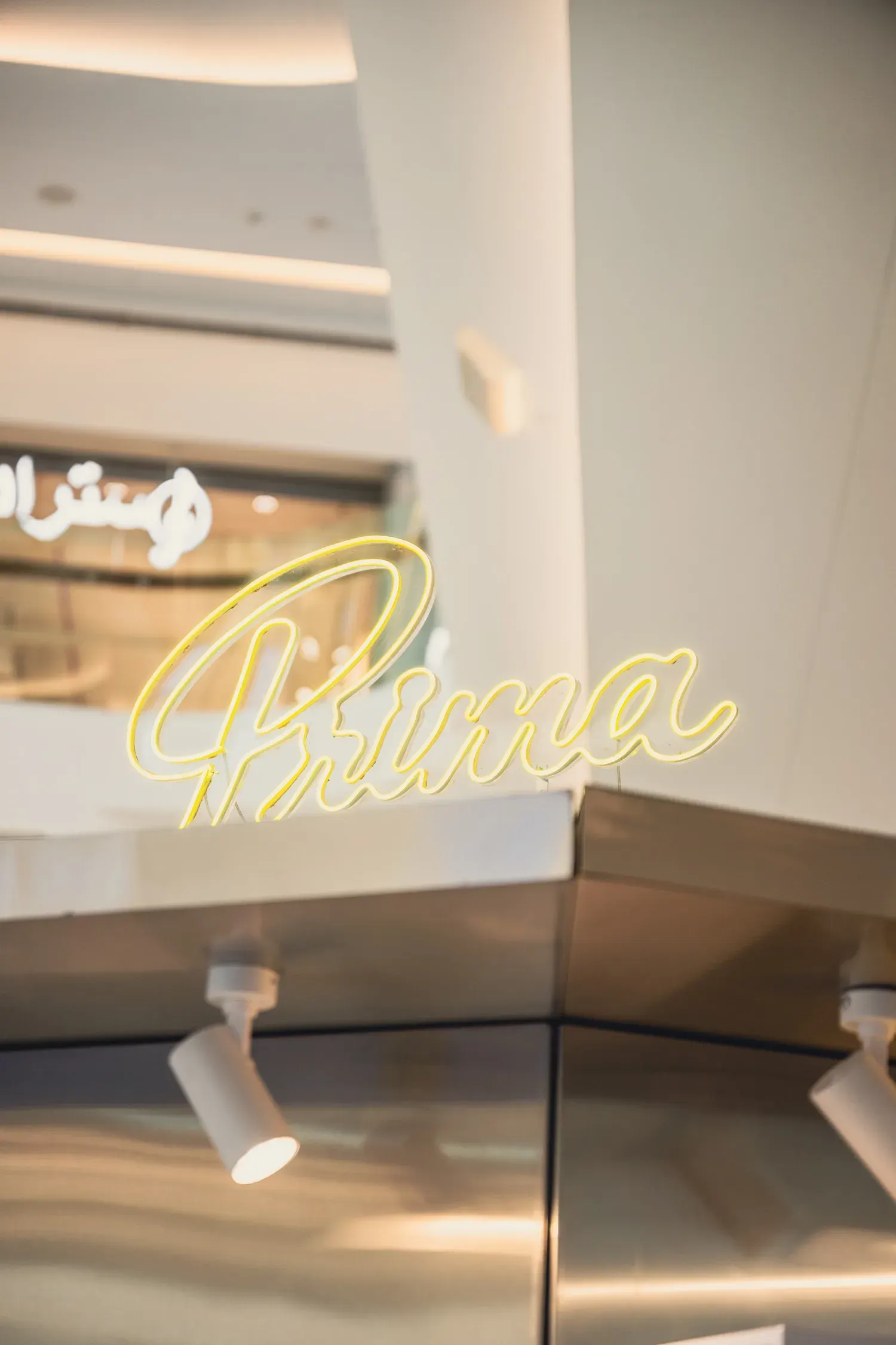 The yellow neon Prima wordmark on the roof of the pop-up booth.