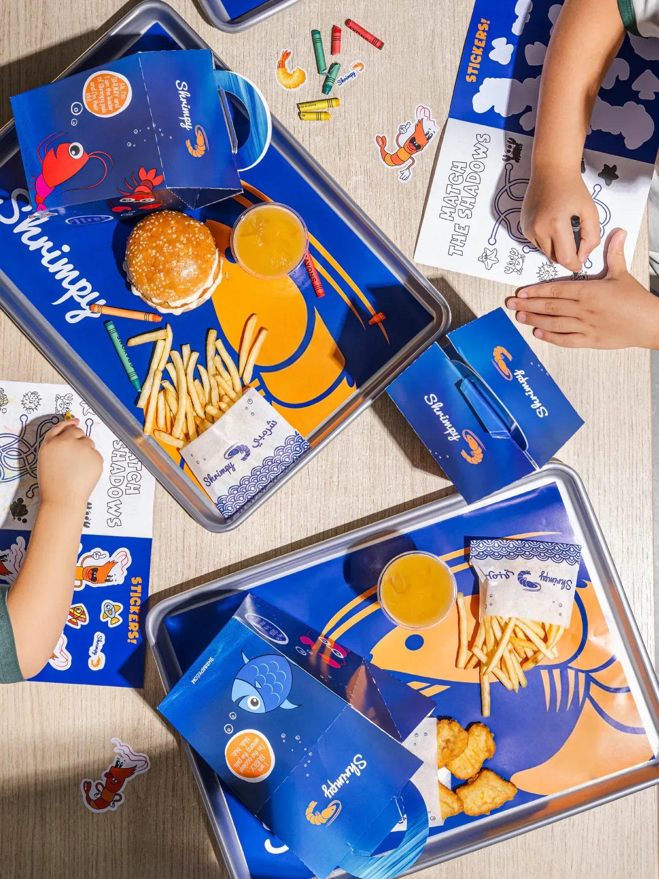 Two trays, four hands and a table mid activity, shot from above.