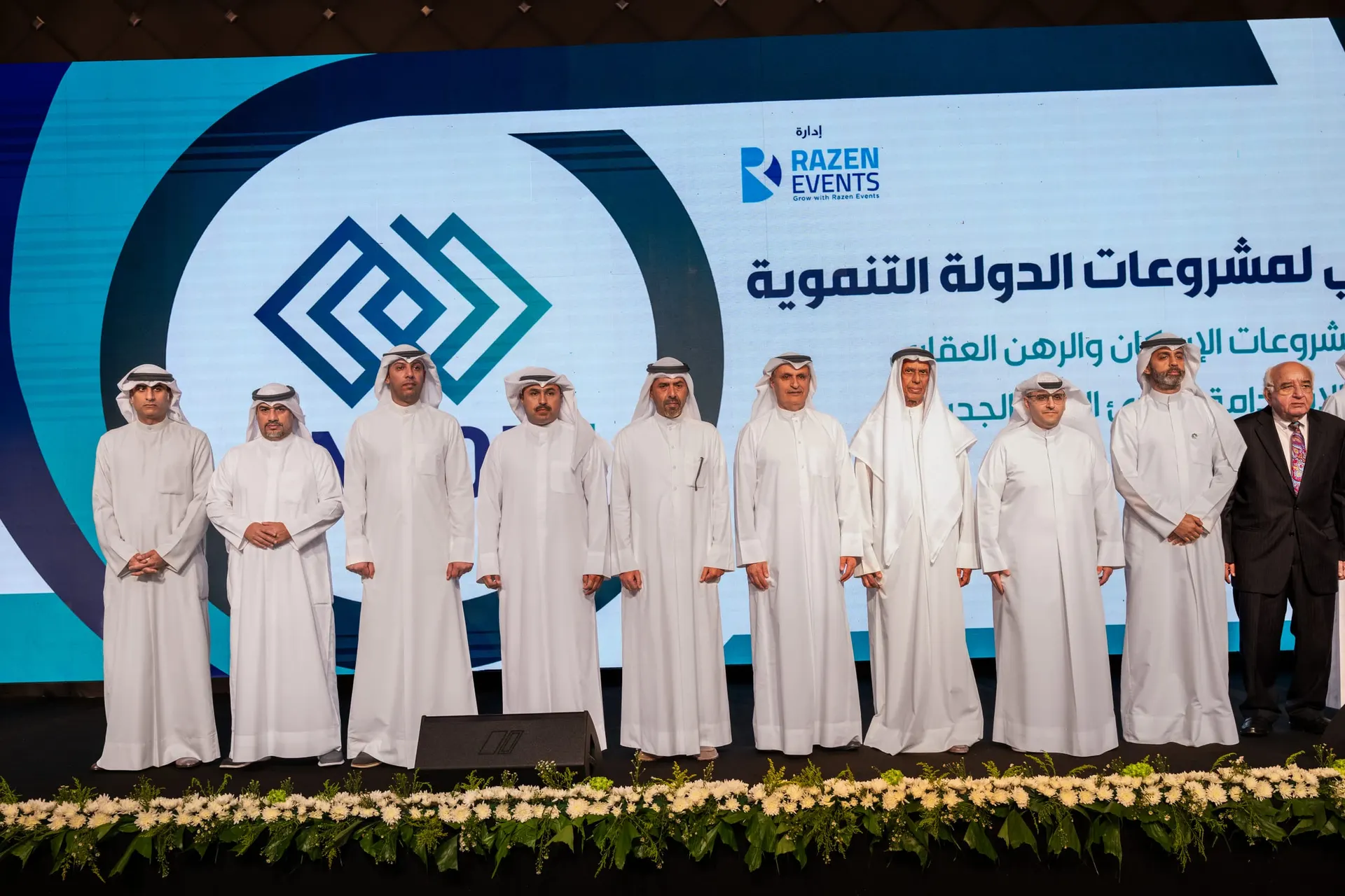 Eleven officials stand on stage in front of an LED wall with the ENCON 5 logo and the forum title on state development projects, organised by Razen Events.